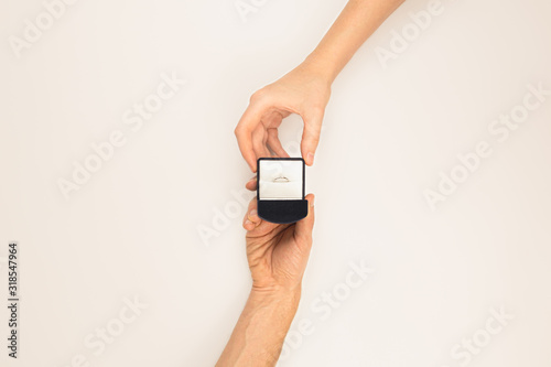 Hand giving a box with a wedding ring to the other hand on white background, top view. .Marriage proposal concept photo