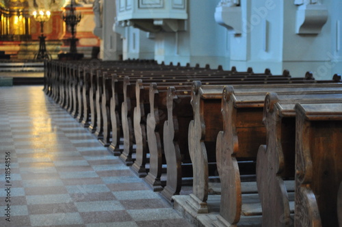 Wooden benches for prayer in religious space with candles
