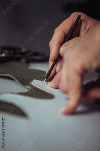 partial view of shoemaker marking leather with special pen near template