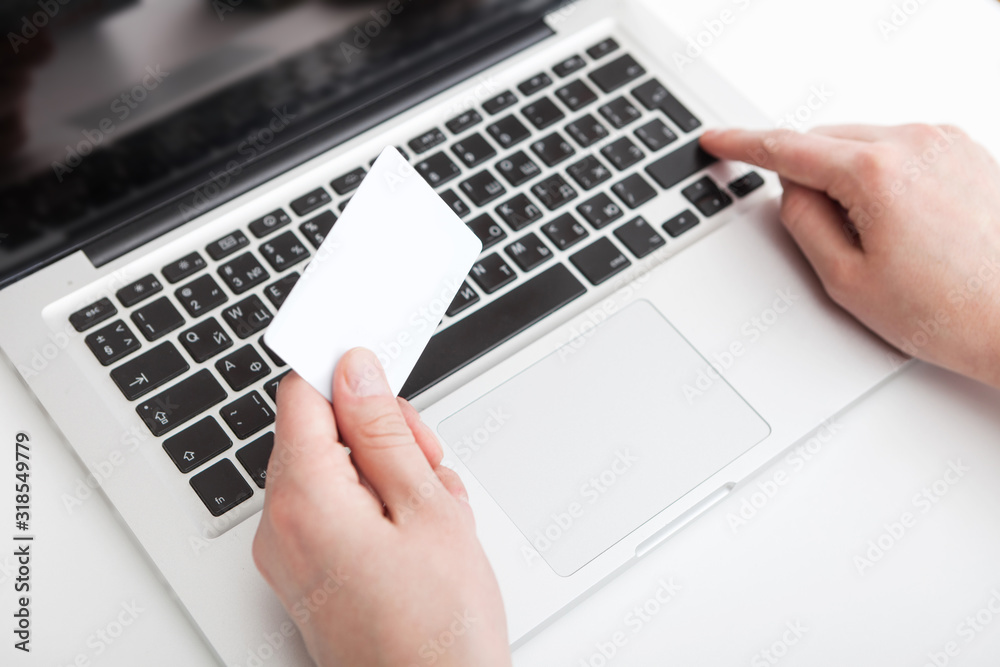 Hands of black man in suit typing credit card number on laptop Hands of black man in suit typing credit card number on laptop
