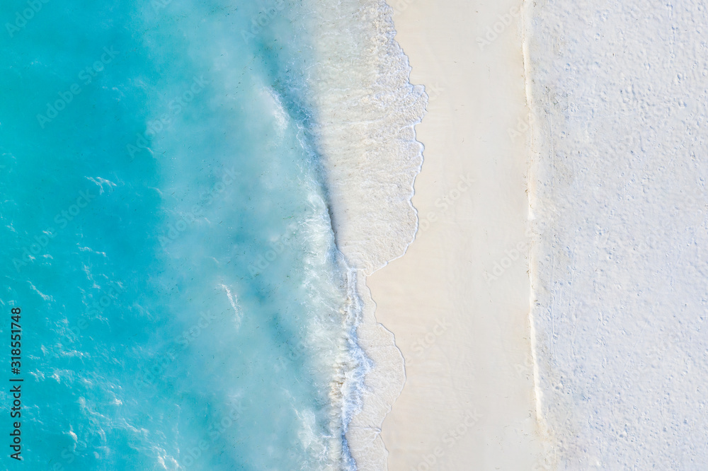 Summer seascape beautiful waves, blue sea water in sunny day. Top view from drone. Sea aerial view, amazing tropical nature background. Beautiful bright sea with waves splashing and beach sand concept