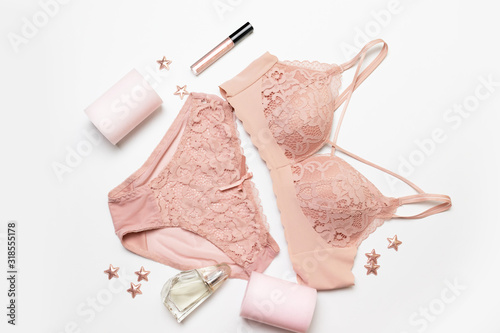 Romantic composition with female pink underwear, candle, lip gloss, perfume and stars decor on a gray background. Valentines day concept