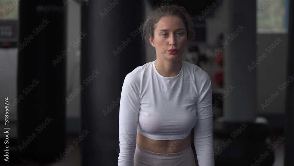 Young caucasian woman exercising and stretching in the gym. Bokeh background. vertical screen