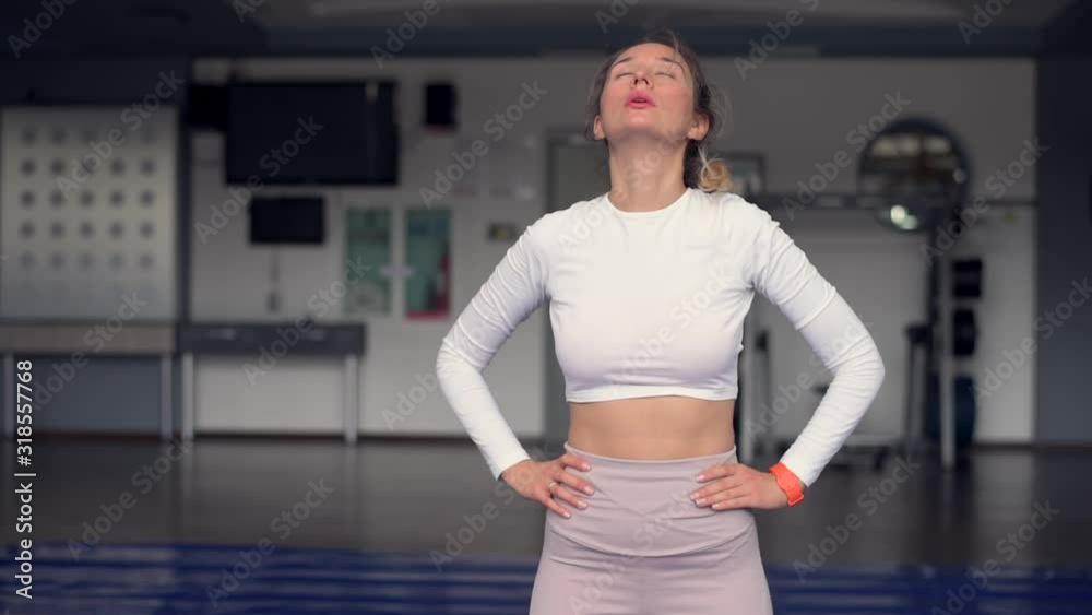 Young caucasian woman exercising and stretching in the gym. Bokeh background. vertical screen