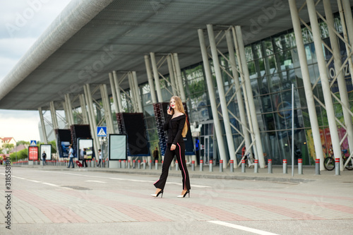 Successful woman walks on a crosswalk. Communicate by mobile phone. Concept for lifestyle, business, movement.