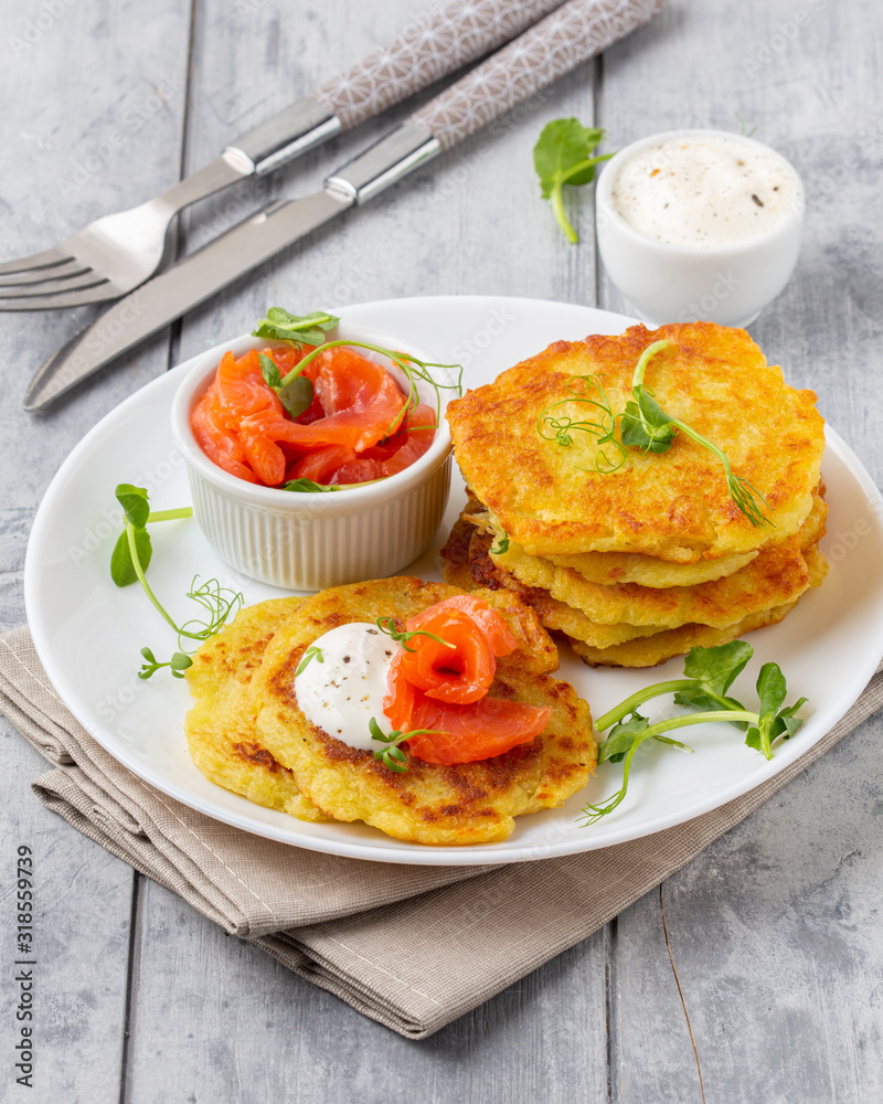 Fried potato pancakes with salmon and sour cream, fritter, roesti, golden crispy crust. Traditional delicious food Fried potato pancakes with salmon and sour cream, fritter, roesti, golden crispy crust. Traditional delicious food