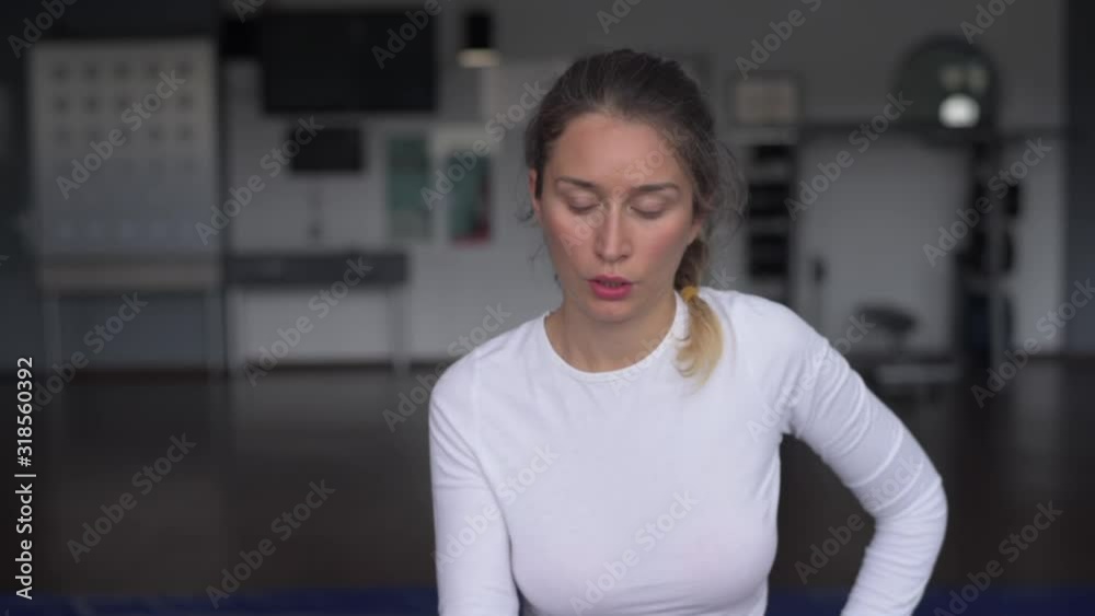 Young caucasian woman exercising and stretching in the gym. Bokeh background. vertical screen