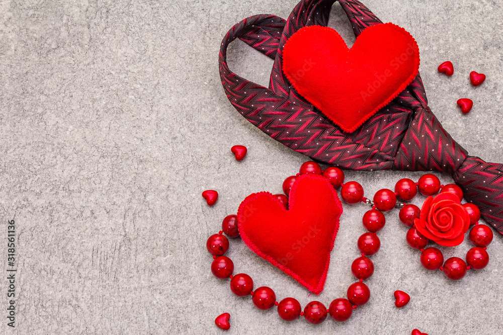 Fototapeta premium Valentines Day concept. Red felt hearts, women beads, men tie. Stone concrete background