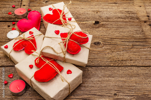 Zero waste gift concept. Valentine Day or Wedding eco friendly packaging. Festive boxes in craft paper with red felt hearts. Vintage wooden background