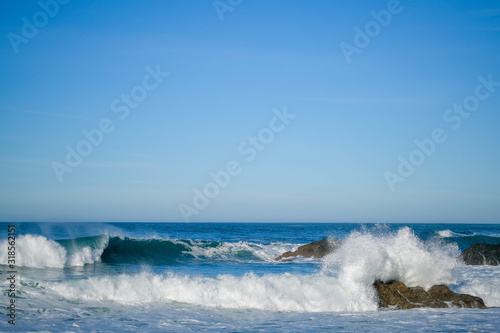 Large ocean waves crash against coastal stones on a clear sunny day on the European coast. Winter holidays on the Atlantic ocean. High waves, surfing in Europe. Tidal bore. Bay of Biscay, Spain. photo