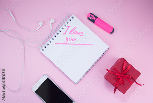 The gift and the smartphone are on a pink background. A gift for a woman. The marker inscription I love you Stylized female flatly. © Elena
