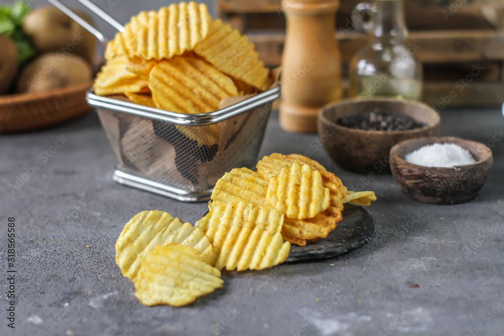 Photo of potato chips on the table with ingredients around. Raw potato tomato. Salt black pepper. On a wooden table. Retro background. On dark board. Studio photography. Image Photo of potato chips on the table with ingredients around. Raw potato tomato. Salt black pepper. On a wooden table. Retro background. On dark board. Studio photography. Image
