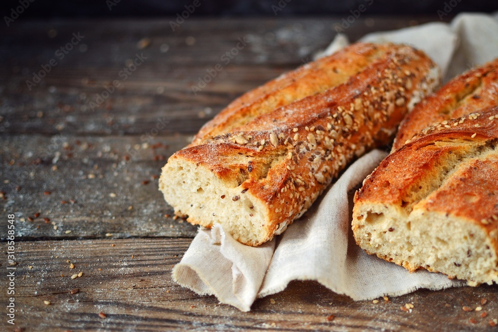 Delicious baguette with sunflower and flax seeds. Crispy Vegetarian Bread. Fresh baked goods on wooden background, closeup with place for text.