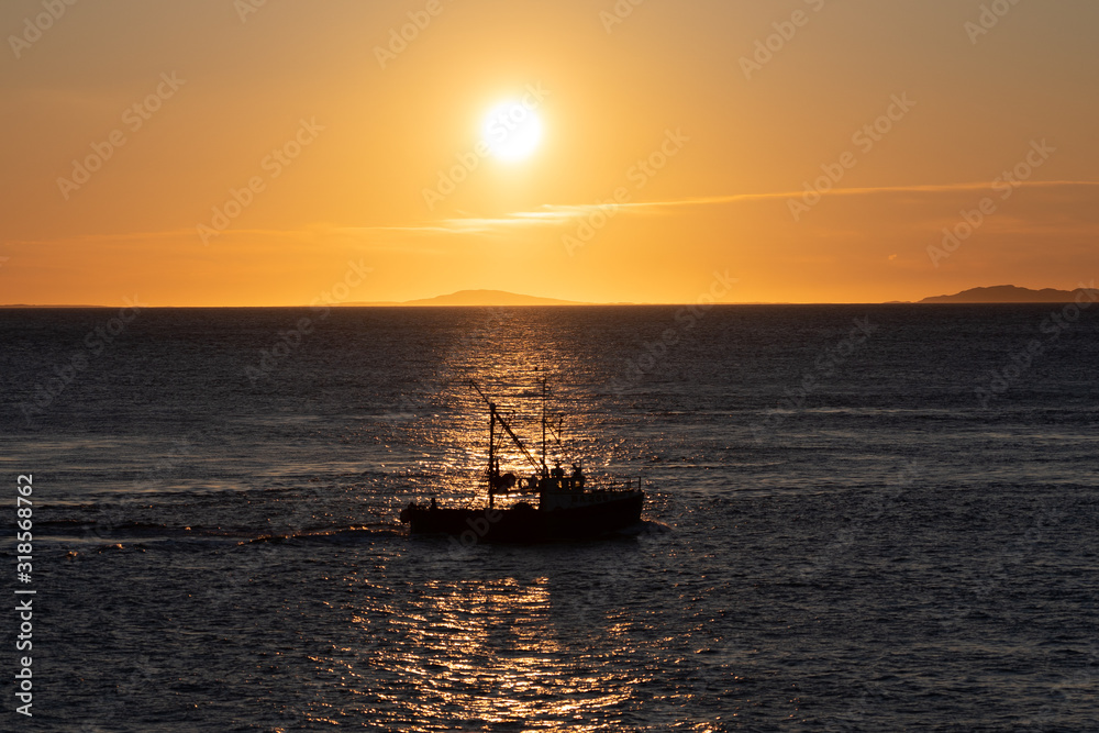 Silhouette of the ship sailing by the sunset