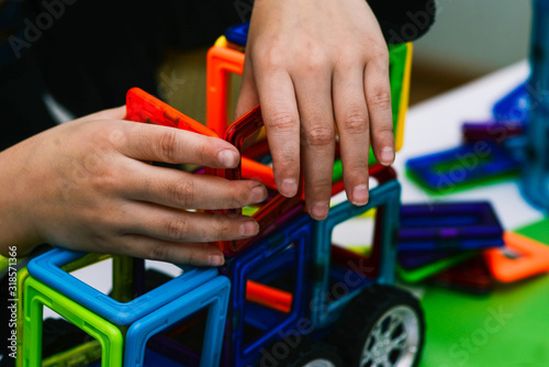The child collects a toy car from the designer. Engineering constructions in miniature. The development of motor skills of hands, thinking, memory and imagination in a child.