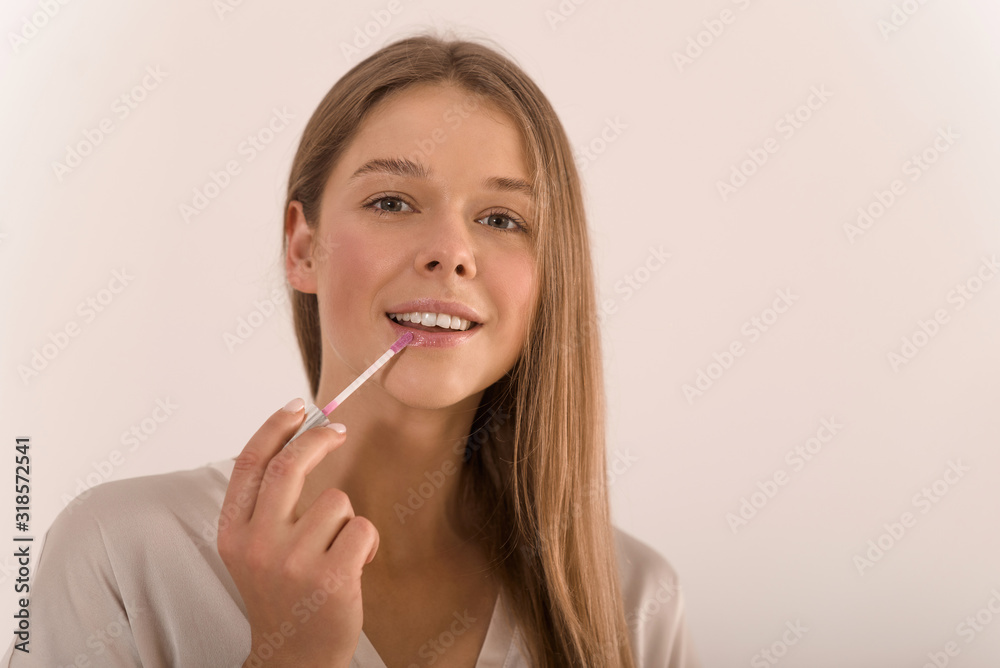 Portrait of a young beautiful woman with lip gloss in her hand. Portrait of a young beautiful woman with lip gloss in her hand.