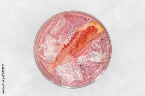 Pink gin tonic vodka soda fruit grapefruit cocktail drink in glass with ice, top view on white background