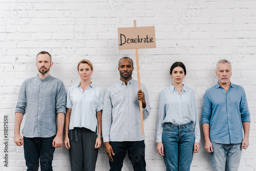 group of people standing near african american man holding placard with demokratie lettering