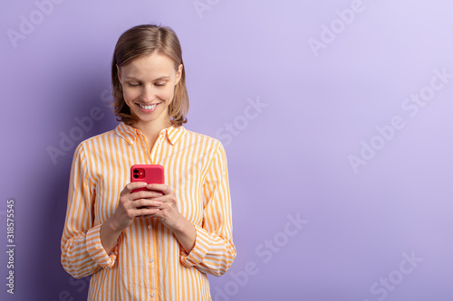 Stunning beautiful caucasian woman holding smartphone in hands, chat with friend and smile, excited, experience positive emotions