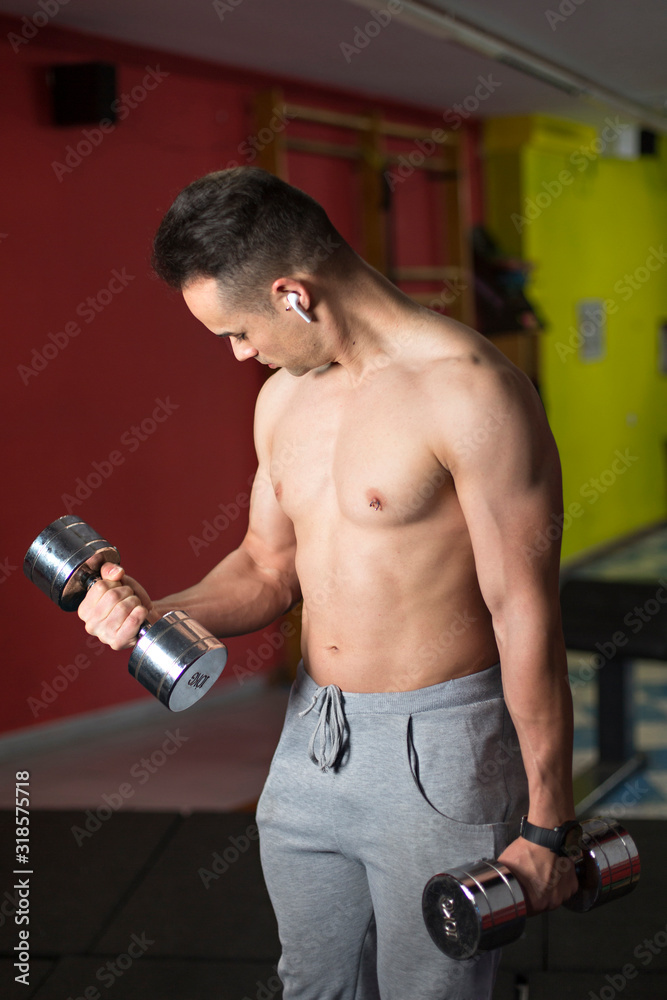 Naklejka premium Young muscular man performing dumbbell exercise.
