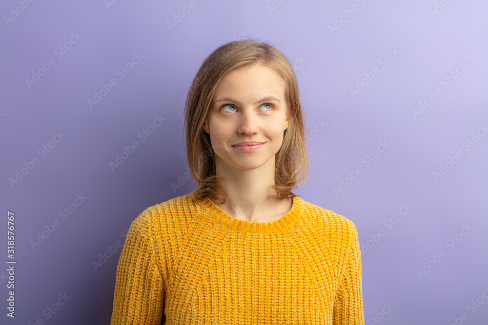 portrait of young attractive dreamy woman in yellow casual blouse stand thinking or dreaming, looking up, having short hair and caucasian appearance, isolated over purple background portrait of young attractive dreamy woman in yellow casual blouse stand thinking or dreaming, looking up, having short hair and caucasian appearance, isolated over purple background