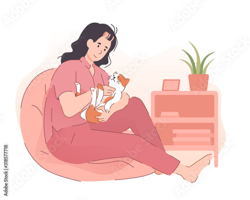 Woman cuddling her cute cat at home. People spending time with pet