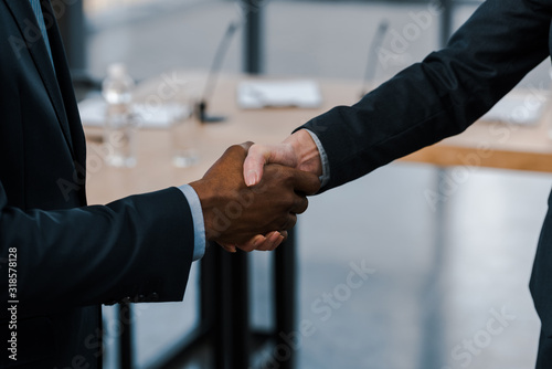 cropped view of businesswoman shaking hands with african american diplomat