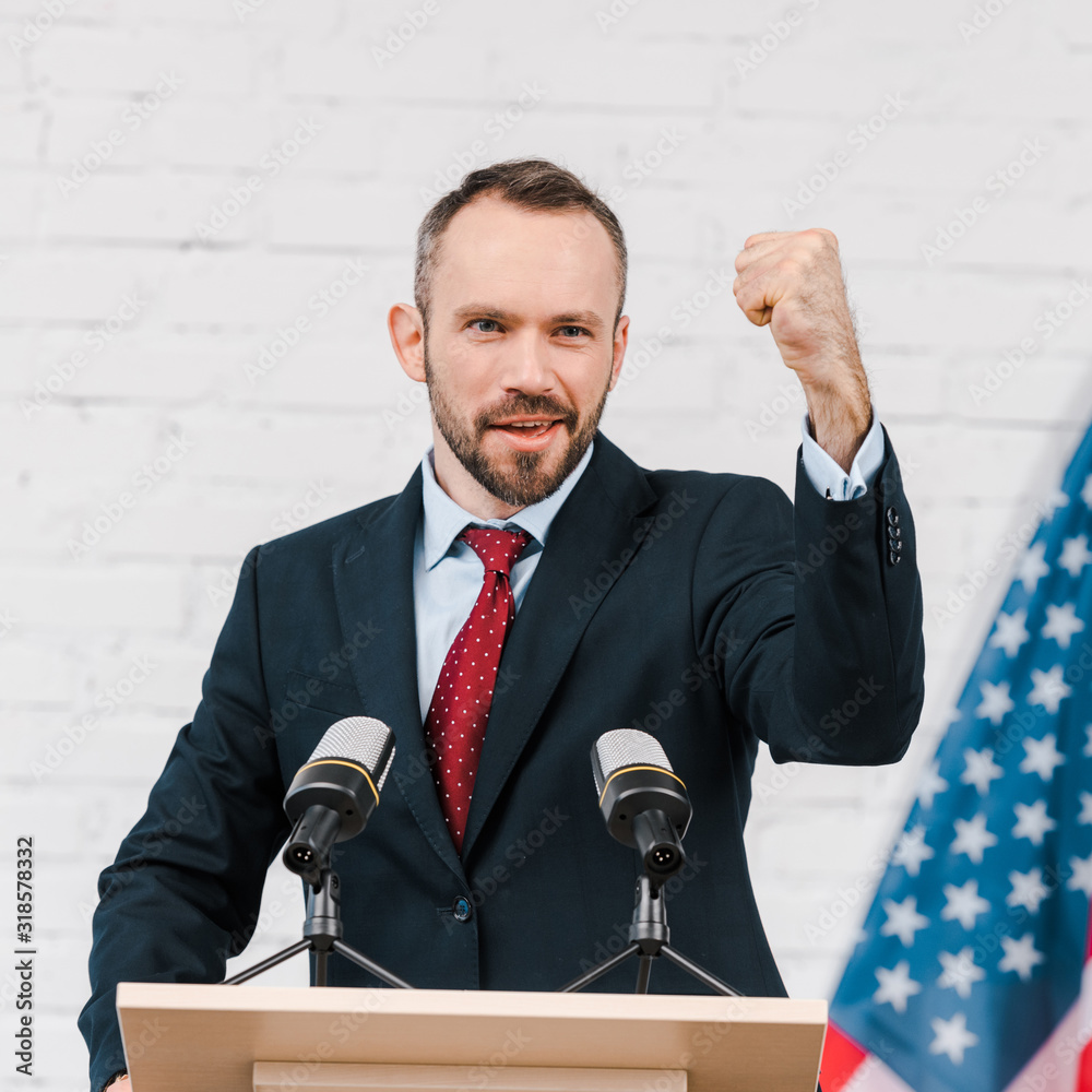 Naklejka premium selective focus of emotional speaker with clenched fist talking near microphones