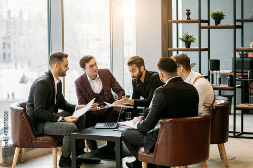 Fototapeta Naklejka Na Ścianę i Meble -  brainstorming time of business team in office, young men gathered together in office for discussing and sharing business ideas, planning strategy in modern boardroom, everyone in formal wear
