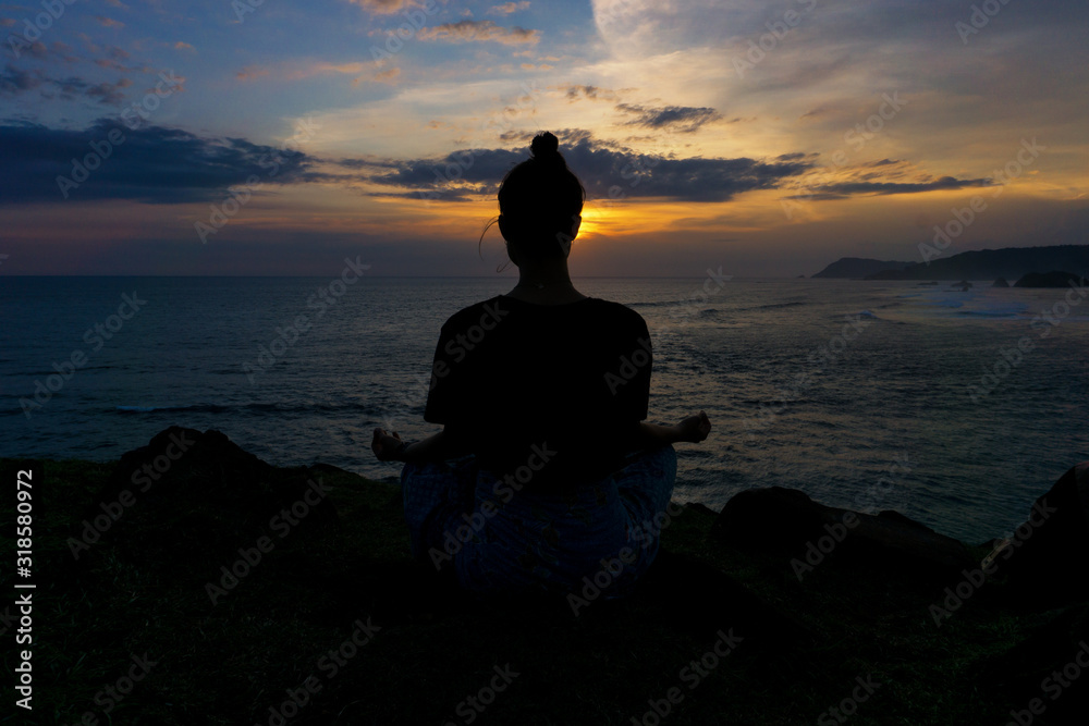 silhouette of young woman yoga at sunset