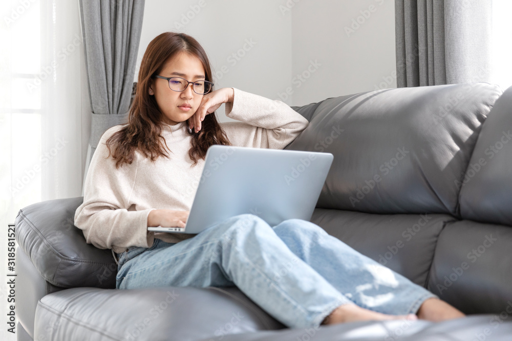 Young woman doing research work for her business, Woman sitting on sofa relaxing while browsing online shopping website. Young woman doing research work for her business, Woman sitting on sofa relaxing while browsing online shopping website.