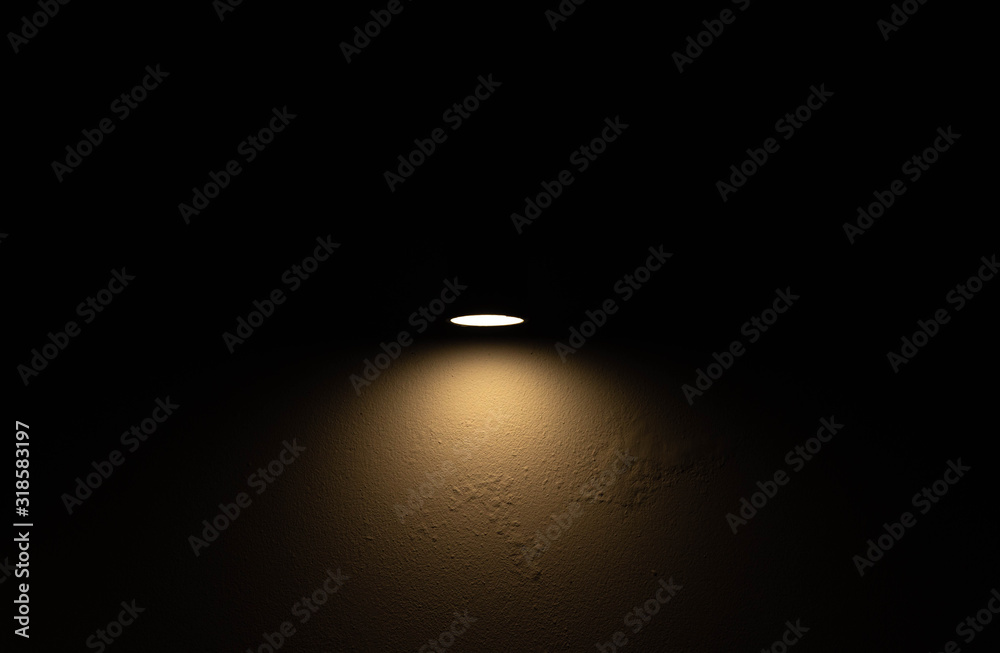 Dark old cement wall with little yellow light from bulb in the middle of wall. Dark old cement wall with little yellow light from bulb in the middle of wall.