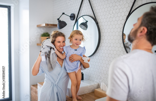 Young family with small daughter indoors in bathroom  talking.