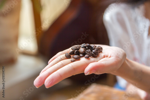 Coffee beans on a woman's hand in a coffee shop.