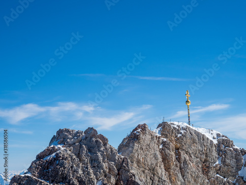 Zugspitz, Germany - Mar 30th, 2019: Zugspitze, the peak of Germany near Garmisch-Partenkirchen with the golden summit cross, and the Austria-Germany border.