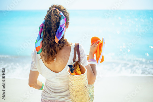 woman with beach straw bag, orange flip flops and bottle of spf photo