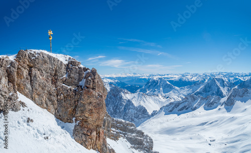 Zugspitz, Germany - Mar 30th, 2019: Zugspitze, the peak of Germany near Garmisch-Partenkirchen with the golden summit cross, and the Austria-Germany border.