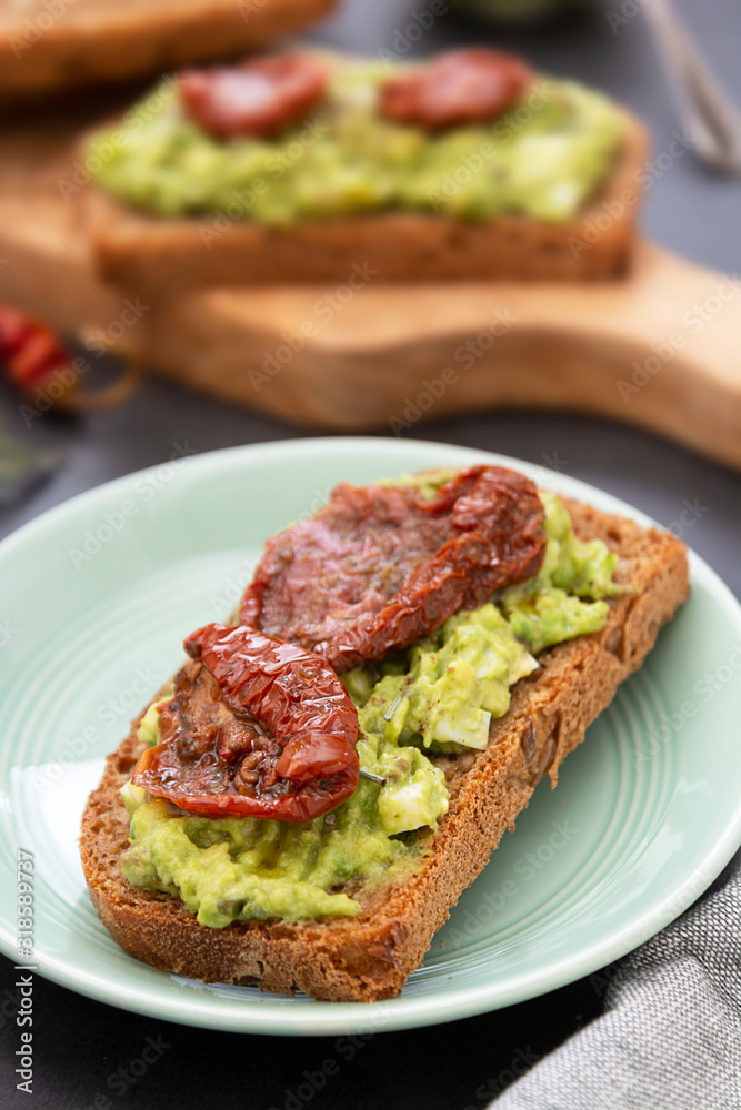 Healthy food. Rye bread with guakomole, avocado pasta and dried tomatoes, on wooden cutting board. Avocado toast. Healthy food. Rye bread with guakomole, avocado pasta and dried tomatoes, on wooden cutting board. Avocado toast.