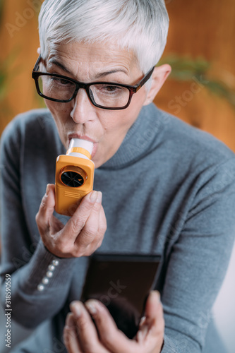 Senior Woman using Spirometer, Measuring Lung Capacity and Peak Expiratory Force photo