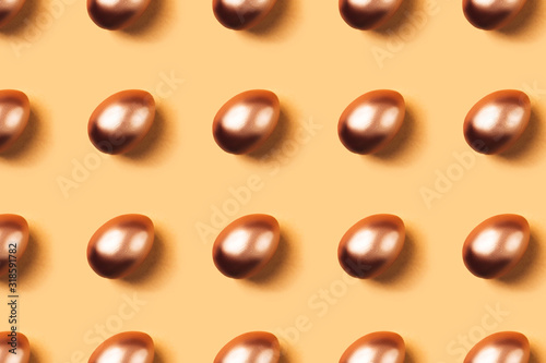 Pattern made of golden eggs on yellow background. Minimal concept. Easter.