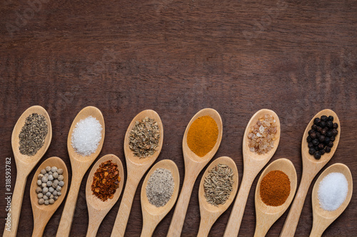 Various spices in wooden spoon on wood table background