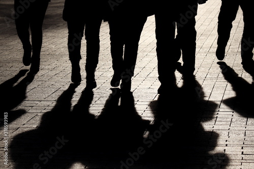 Silhouettes and shadows of people on the street. Crowd walking down on sidewalk, concept of strangers, crime, society, epidemic, population photo