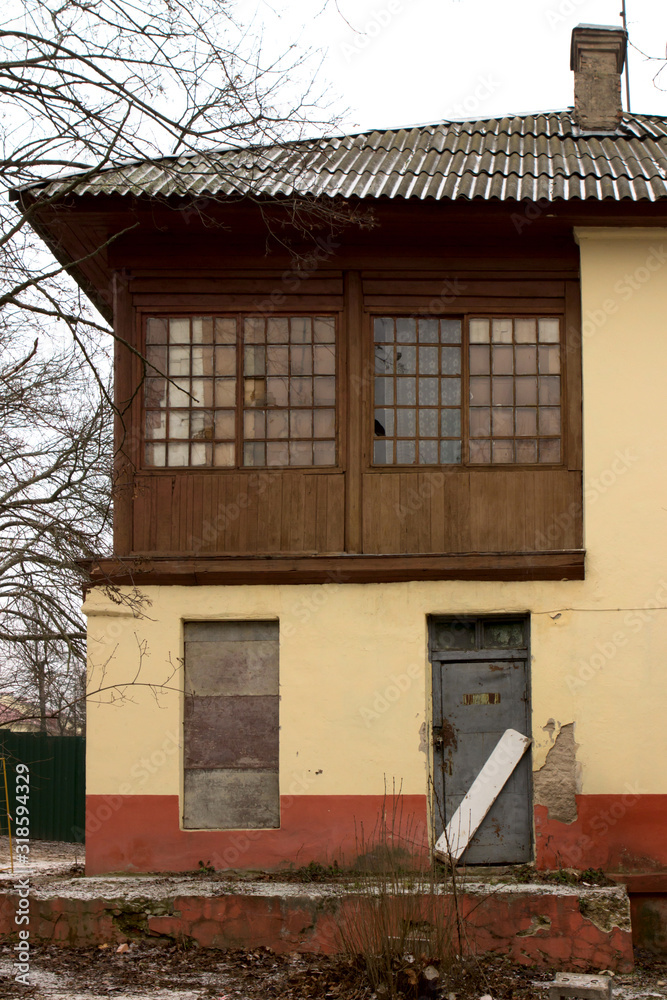 A two-story, yellow, wooden recently abandoned house in an urban environment. The view from the outside is close. A two-story, yellow, wooden recently abandoned house in an urban environment. The view from the outside is close.