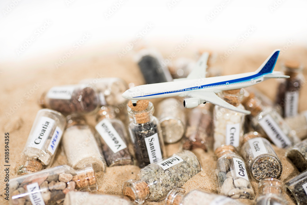 Glass test-tube with sand of different summer vacation countries. Located in sand with small airplane. Glass test-tube with sand of different summer vacation countries. Located in sand with small airplane.