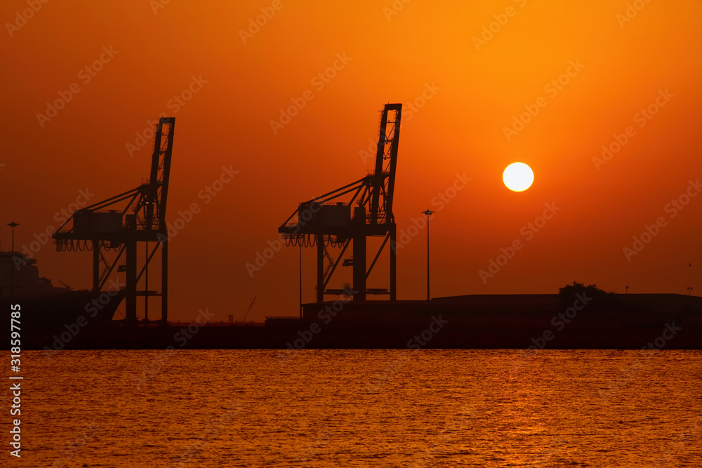 Industrial cargo port and silhouette of cranes at sunset int Dubai Industrial cargo port and silhouette of cranes at sunset int Dubai