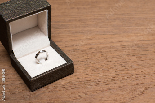 Diamond wedding ring in the box on wooden table.