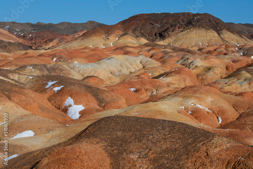 Eroded desert landscape with clay layers and snow