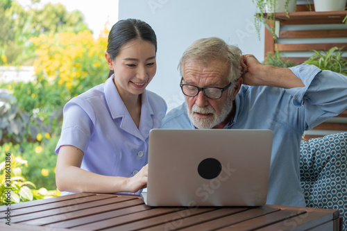 Young nurse take care senior man at home, Senior man with nurse are checking health results online by laptop, Health care concept photo