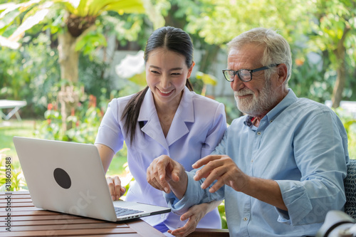 Young nurse take care senior man at home, Senior man with nurse are checking health results online by laptop, Health care concept
