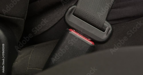 Man Fastening Seat Belt a Close up of Hand Bucked up and Unbuckled Sitting in a Car Concept of Travel Safety Shot on Red photo